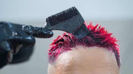 Photo for Close-up of the process. The hairdresser dyes the hair of an Asian woman in pink. Short extreme haircut - Royalty Free Image