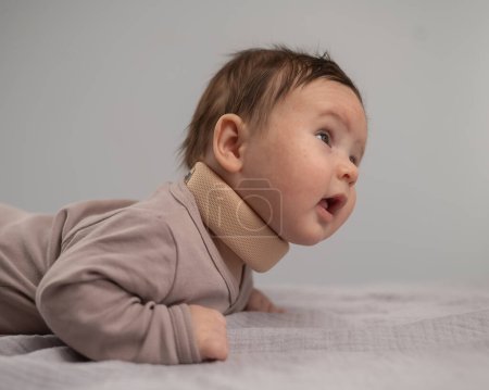 Porträt eines Neugeborenen auf dem Bauch liegend in einem orthopädischen Kragen