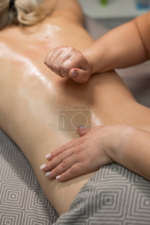 Téléchargez les photos : Femme caucasienne subissant un massage manuel à l'huile du dos. Photo verticale - en image libre de droit