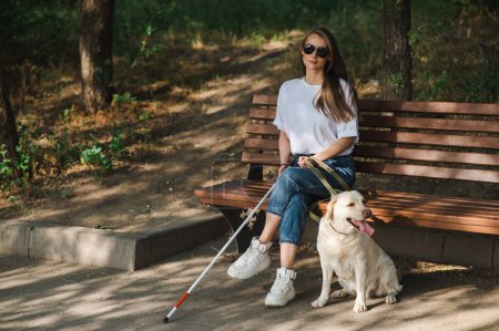 Photo for Blind caucasian woman sitting on bench with guide dog - Royalty Free Image