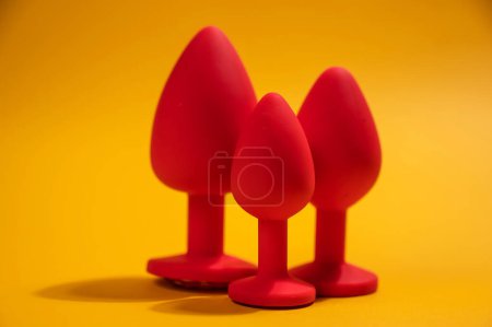 Foto de Three size silicone red butt plugs on an orange background - Imagen libre de derechos