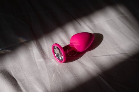 Foto de Plug anal de silicona rosa en una sábana blanca - Imagen libre de derechos