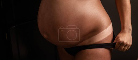 Photo for Pregnant woman pulls back her panties showing instant tan - Royalty Free Image