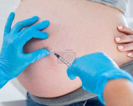 Doctor gives an injection in the stomach of a pregnant woman