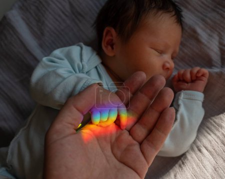 Ein Mann hält seine neugeborenen Söhne an der Hand. Lichtstrahl durch ein Prisma