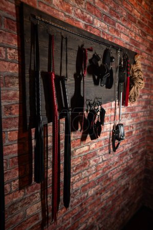 A set of BDSM equipment hanging on the wall. Vertical photo