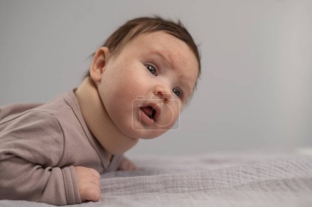 Porträt eines Neugeborenen auf dem Bauch liegend in einem orthopädischen Kragen
