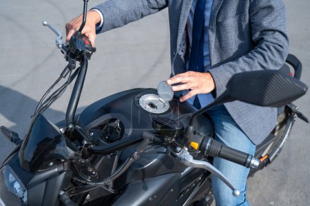 A man opened the charging socket on an electric motorcycle