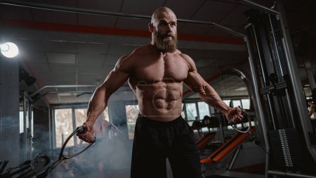 Bald Caucasian bodybuilder training chest using cable crossover in gym