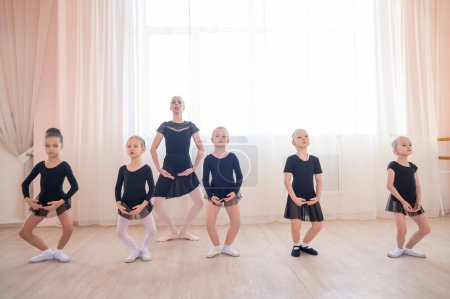 Childrens ballet school. Caucasian woman teaching ballet to little girls