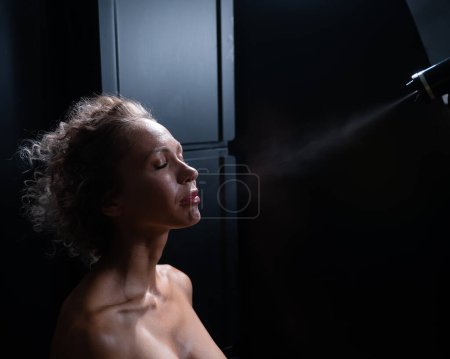 Foto de Un maestro aplica pintura tintada a la cara de una mujer caucásica. Procedimiento de bronceado instantáneo. - Imagen libre de derechos