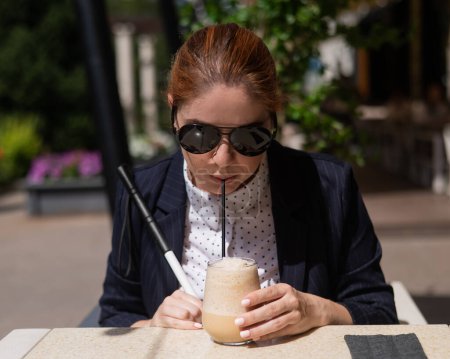 Mujer ciega en traje de negocios bebiendo café helado en café al aire libre