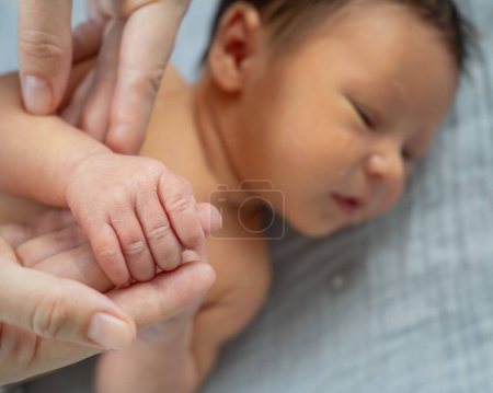 Ein neugeborener Junge hält den Finger seiner Mutter. Nahaufnahme der Hände