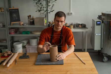 Potter esculpe un cilindro modelado de arcilla