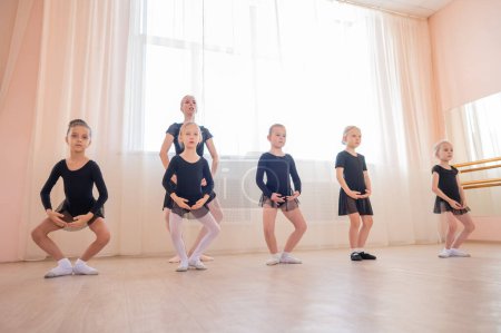 Childrens ballet school. Caucasian woman teaching ballet to little girls