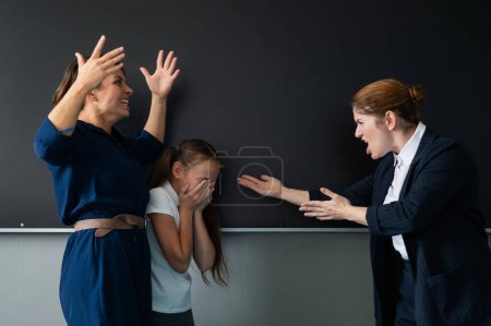 A female teacher and a students mother yell at each other at the blackboard. The schoolgirl is crying
