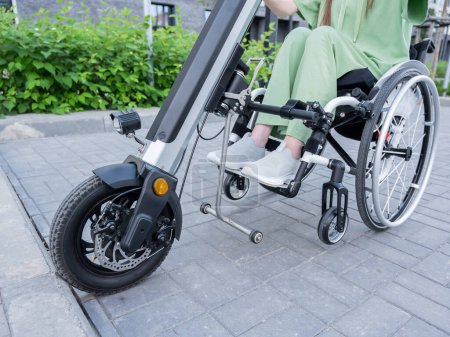 Foto de Una mujer sin rostro en silla de ruedas con un dispositivo de asistencia para el control manual. Handbike eléctrico - Imagen libre de derechos