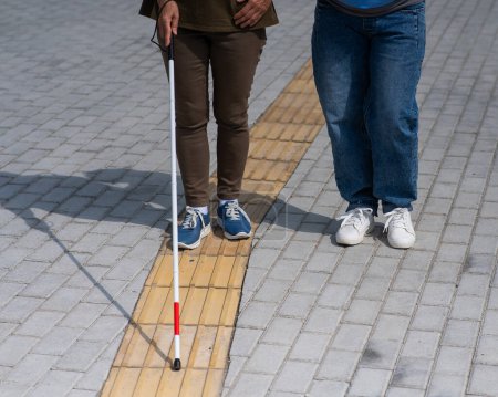 Primer plano de las piernas de una mujer que acompaña a una anciana ciega al aire libre