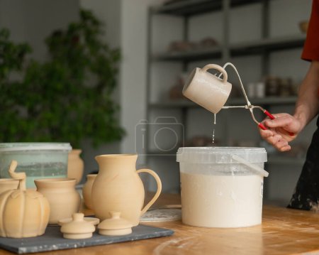 Téléchargez les photos : Gros plan sur les mains d'un potier vitrant une tasse en céramique - en image libre de droit