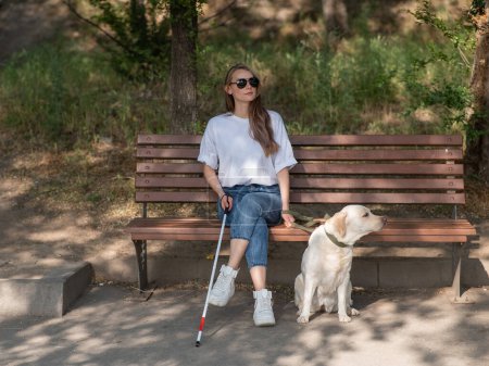 Blind caucasian woman sitting on bench with guide dog