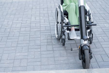 Foto de Una mujer sin rostro en silla de ruedas con un dispositivo de asistencia para el control manual. Handbike eléctrico - Imagen libre de derechos