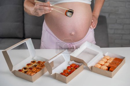 Una mujer embarazada está en una mesa con panecillos. Primer plano del vientre