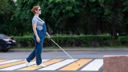 Blinde Schwangere überquert Straße an einer Kreuzung mit Blindenstock