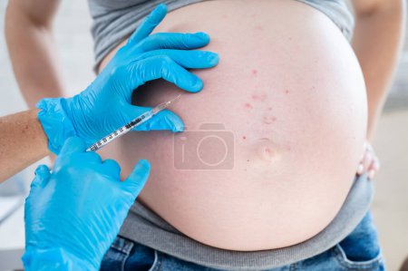 Doctor gives an injection in the stomach of a pregnant woman