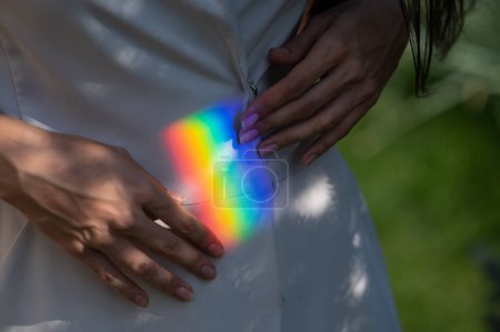 Mujer sin rostro captura de rayos del arco iris con sus manos al aire libre