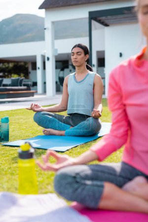 Diverse Freunde praktizieren Yoga und meditieren im Garten. Gesundheit, Feiern, Freundschaft, Inklusivität und Lifestylekonzept.