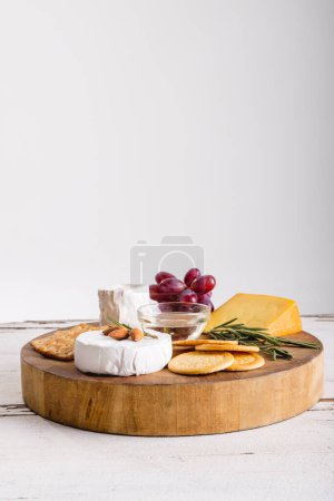 Käse von Trauben mit Kräutern und Crackern auf Holzbrett vor weißem Hintergrund, Kopierraum. unverändert Nahrungsmittel, Obst und Milchprodukte.