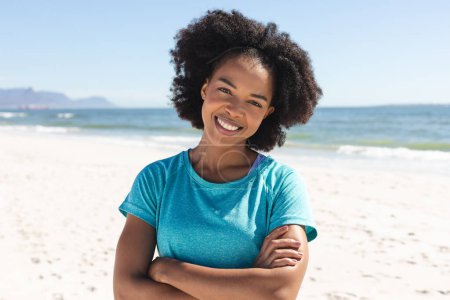 Portrait of happy african american woman looking at camera and smiling sunny on beach. Summer, lifestyle, free time and vacation, unaltered.