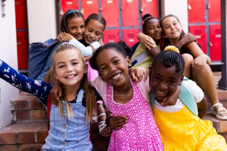 Portrait de diverses écolières heureuses embrassant dans le vestiaire de l'école primaire. École, apprentissage, enfance, amitié et éducation, intacte.