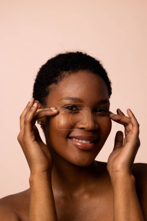 African american woman with short hair looking away smiling and touching temples. Femininity, face, facial expressions, body, skin, makeup, fashion and beauty, unaltered.