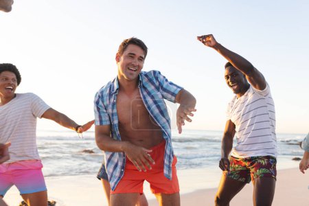 Young men enjoy a lively moment on the beach. Their laughter and dynamic poses capture the essence of carefree outdoor fun.