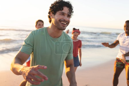 Diverse friends enjoy a sunny day at the beach. The group's laughter and active engagement create a vibrant outdoor scene.