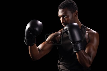 African American man in a boxing stance, with copy space. His intense focus exemplifies determination and strength in a gym setting.
