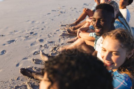 Diverse friends enjoy a beach sunset. Laughter and relaxation fill the air as they unwind outdoors.