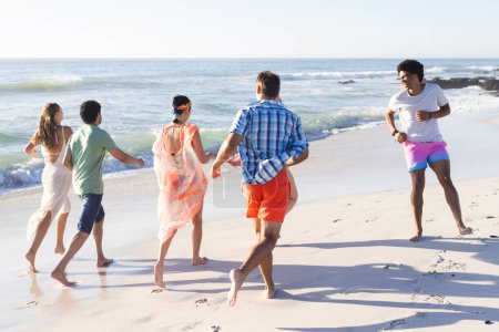 Vielfältige Freunde genießen einen Tag am Strand. Lachen erfüllt die Luft, während sie am Ufer entlang laufen und die Freude des Sommers umarmen.