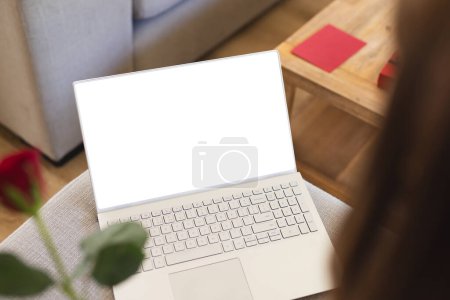 A laptop with a white screen is open on a wooden table, with copy space. Ideal for presenting digital content or advertising, the blank screen offers a versatile backdrop for designers and marketers.