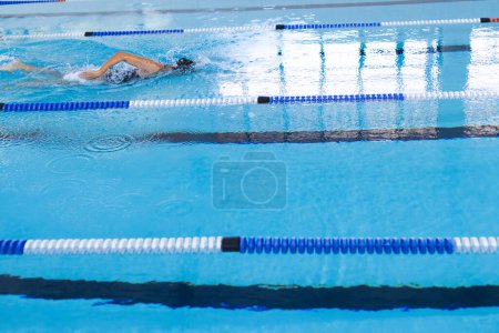Swimmer in action at a pool competition, with copy space. The focus is on the athlete's technique and the intensity of the race.