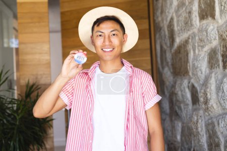 Young Asian man shows a 'vote' badge proudly. Captured at home, his gesture promotes civic engagement and the importance of voting.