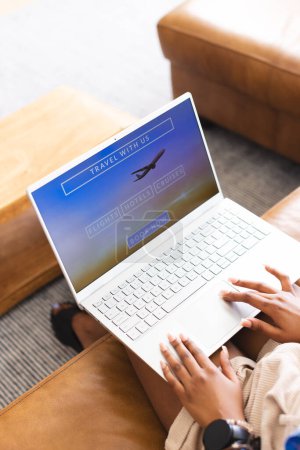 Eine Person surft auf einem Laptop auf einer Reise-Webseite. Auf einem gemütlichen Sofa scheint der Einzelne angesichts von Flügen, Hotels und Kreuzfahrten einen Urlaub zu planen..