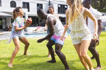 Diverse group of friends enjoy a playful game of football in a sunny backyard. Laughter and friendly competition fill the air as they embrace the joy of outdoor activities.