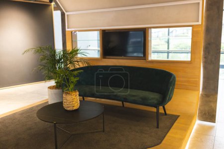 Keine Menschen anwesend, nur ein stilvolles Zimmer mit grünem Sofa und rundem Couchtisch. Eine Topfpflanze verleiht dem Raum einen Hauch von Natur, unverändert