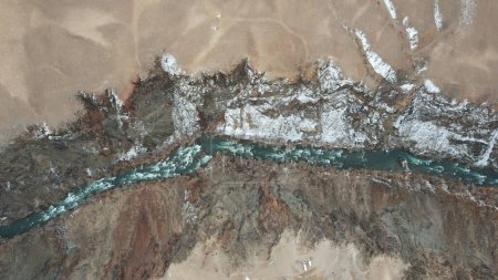 Foto de El Gran Cañón en la estepa con el río Esmeralda. Una grieta en el suelo con piedras negras, el color verde del río. Los arbustos crecen en lugares. Hay turistas y autobuses en el borde. Kazajstán - Imagen libre de derechos