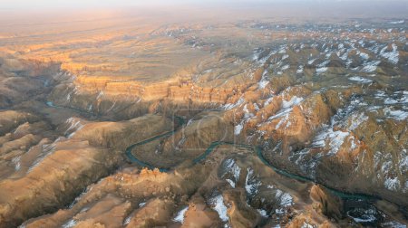 Téléchargez les photos : Charyn Grand Canyon aux parois rocheuses orange. Vue aérienne depuis le drone des parois abruptes du canyon, des fissures et des tunnels. Il y a de la neige par endroits. Le soleil brille de mille feux. Frère du Grand Canyon - en image libre de droit