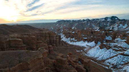 Téléchargez les photos : Charyn Grand Canyon aux parois rocheuses orange. Vue aérienne depuis le drone des parois abruptes du canyon, des fissures et des tunnels. Il y a de la neige par endroits. Beau coucher de soleil et lever de soleil. Frère du Grand Canyon - en image libre de droit