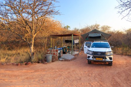 Foto de Waterberg Plateau Campsite, Namibia - 09 de octubre de 2018: Coche típico de alquiler 4x4 en Namibia equipado con equipo de camping y una tienda de campaña en el camping. - Imagen libre de derechos