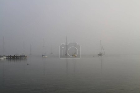 algunos barcos de vela en la luz de fondo en el lago Ammersee en la niebla de la mañana
